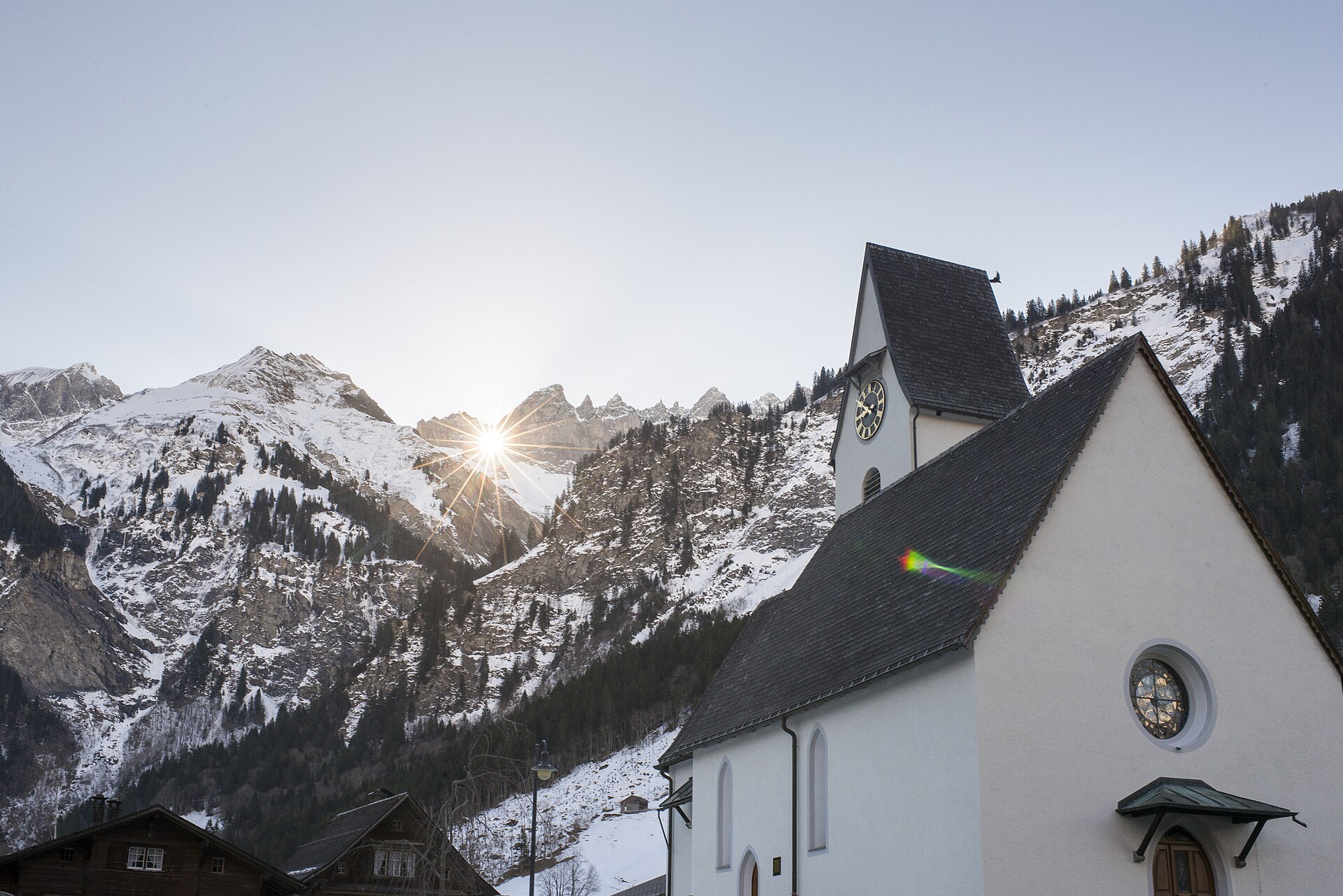 The church at Elm, Switzerland, with the sun breaking over the Tschingelhörner ridge behind the village.